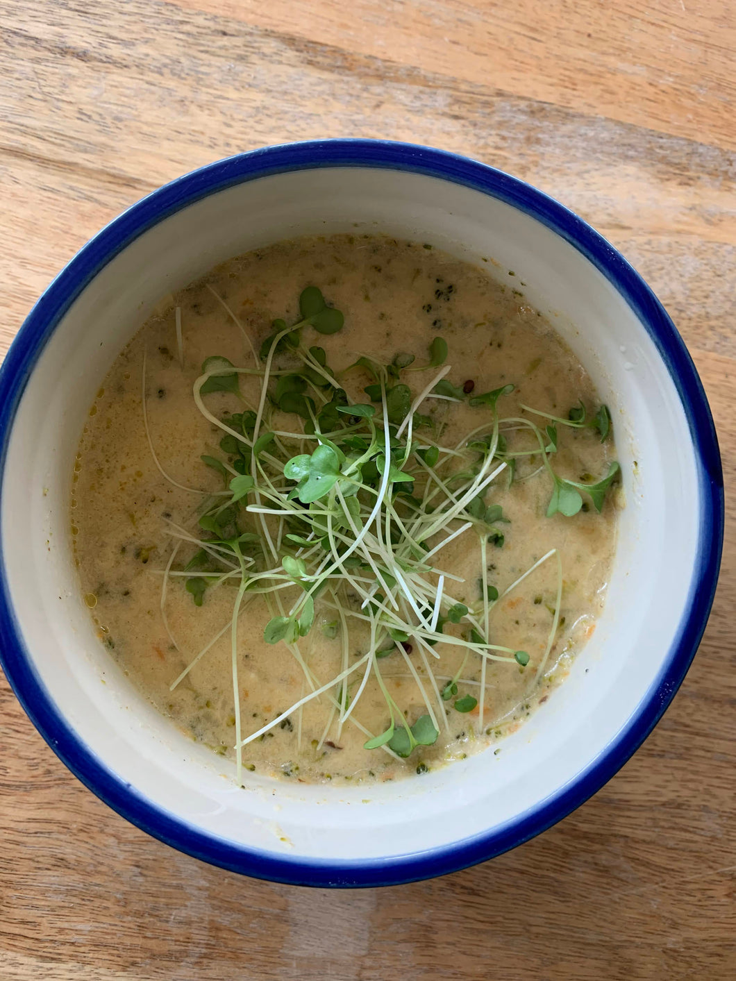 Broccoli cheese soup in a bowl with broccoli microgreens