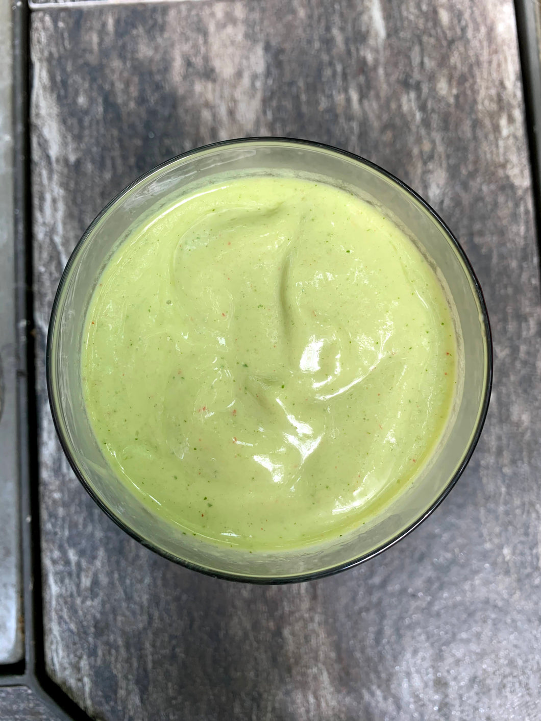 Green smoothie in a glass on a table.