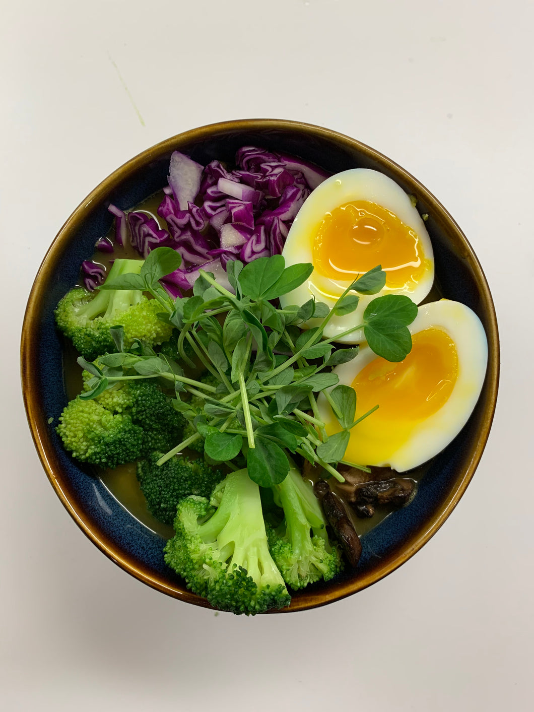 Ramen soup in a bowl topped with dun pea microgreens.